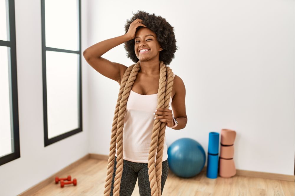  african american woman with afro hair at the gym training with battle ropes 