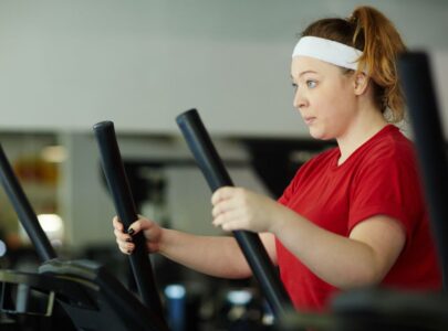 Side view portrait of determined overweight woman working out in gym