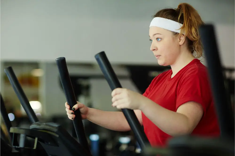 Side view portrait of determined overweight woman working out in gym