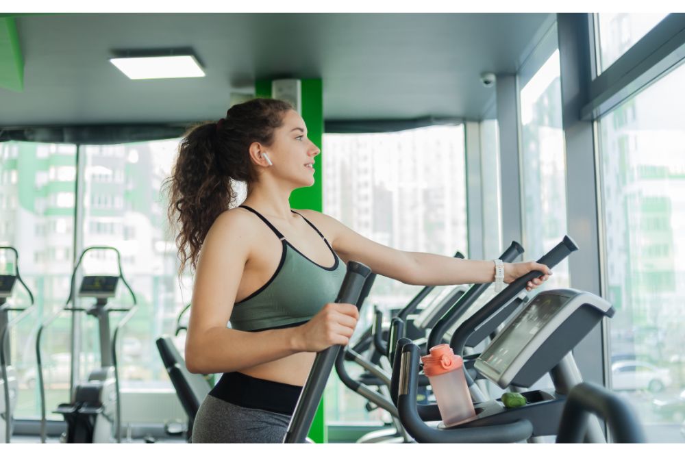 attractive woman warming up on an elliptical exercise machine in the gym