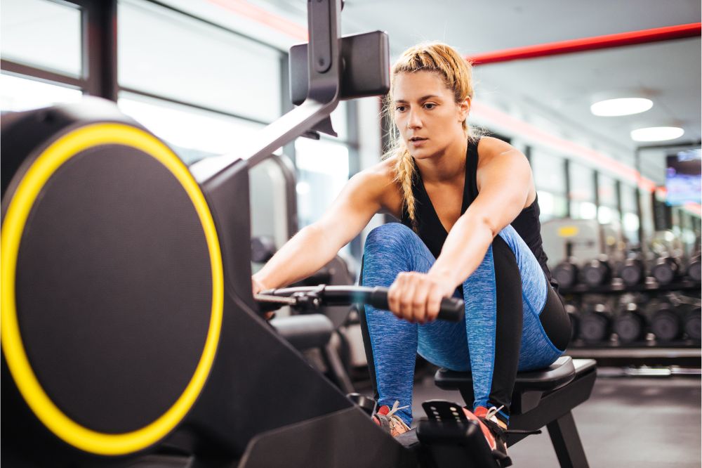 Young sporty woman working out on a rowing machine in a gym